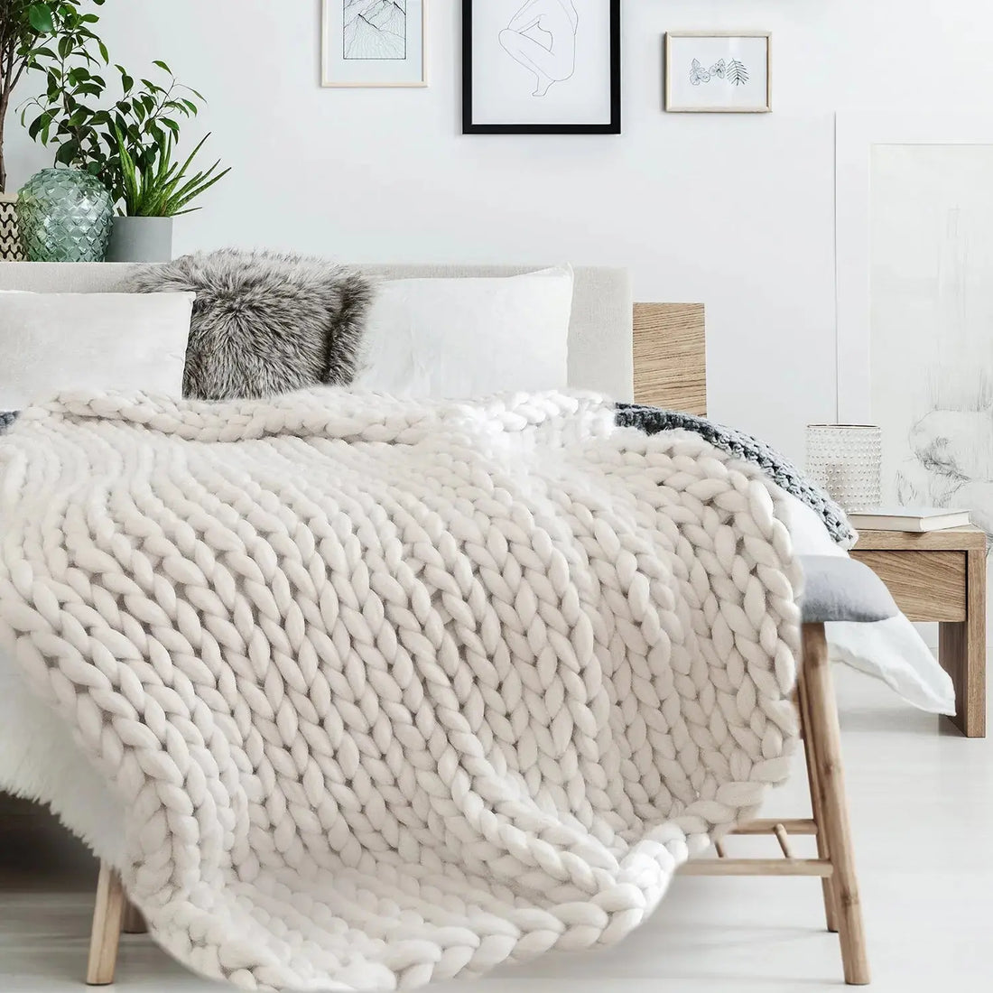 Plaid grosse maille écru posé sur un lit douillet